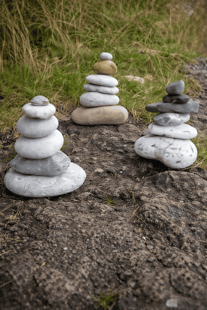three carefully balanced stone cairns arranged on a rugged rock surface outdoors. 