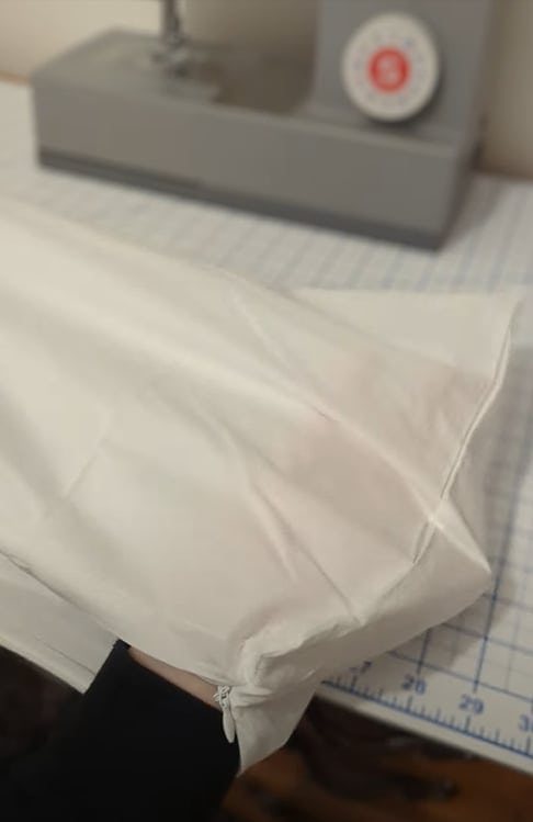 Turning the sewn pillow cover right side out through the zipper opening.