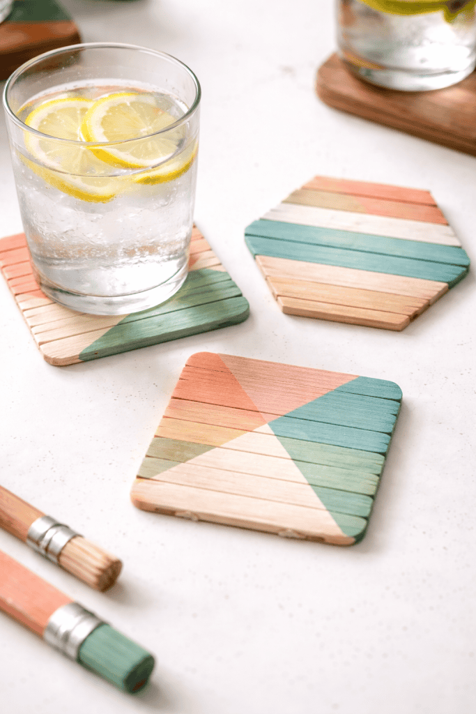 DIY craft stick coasters arranged on a bright white table.