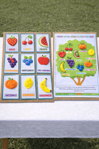 Fruit of the Spirit playdough crafts displayed side by side on a white outdoor table, showing fruit cards and a playdough tree mat activity for kids.