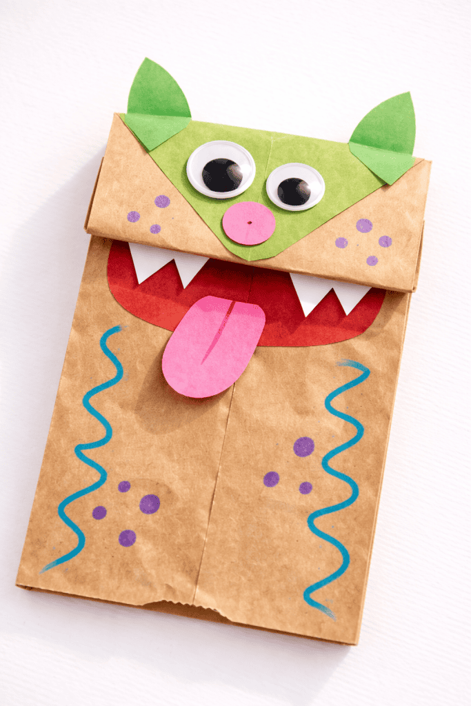 a kid-made paper bag puppet placed on a plain bright white table