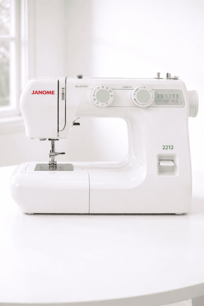 Janome 2212 mechanical sewing machine on white table against neutral background