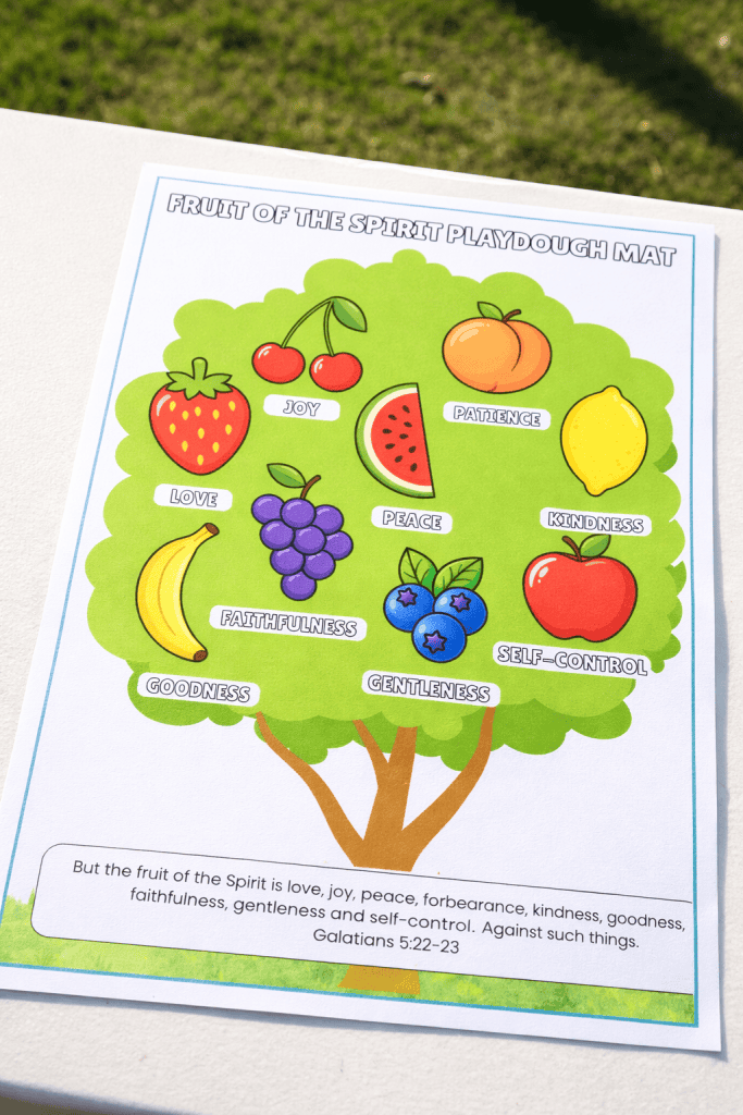 fruit of the spirit playdough mat printable with tree and labeled fruits from Galatians 5:22–23 on a white table outdoors