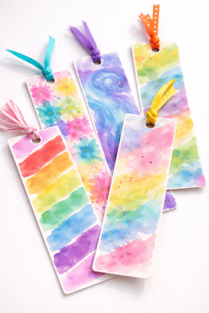 kid-made watercolor bookmarks arranged on a plain bright white table.