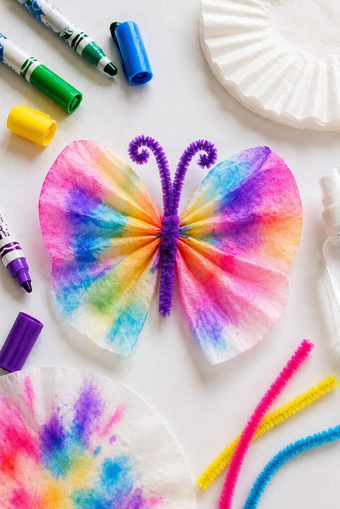 a finished butterfly made from a round coffee filter that has been colored with washable markers and lightly misted with water.