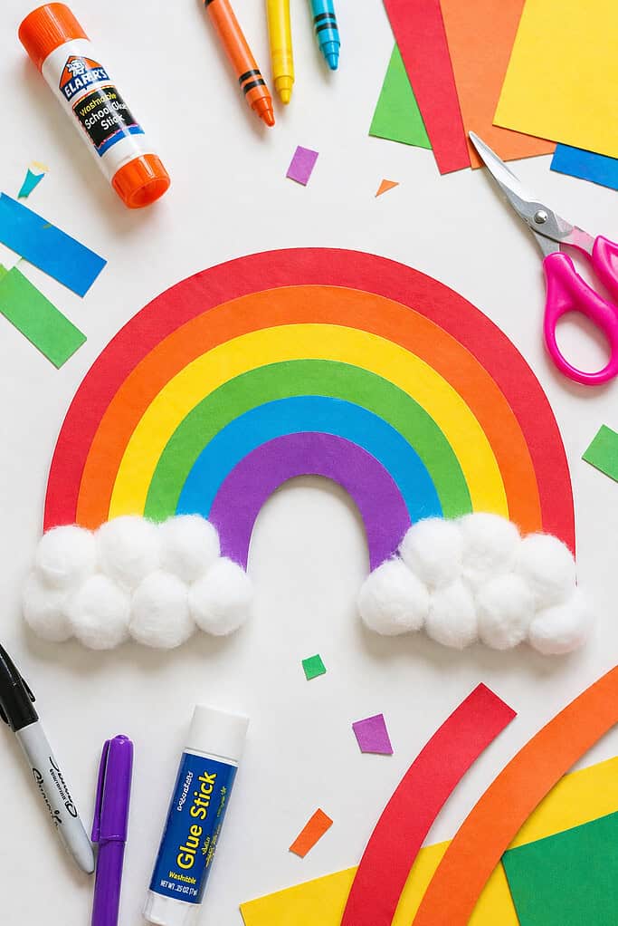 a vibrant handmade rainbow created from layered, arched strips of construction paper in classic rainbow order: red, orange, yellow, green, blue, and purple