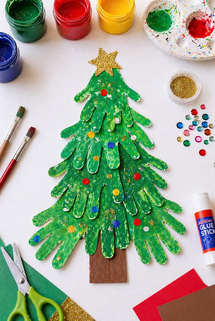 a finished Christmas tree made from multiple green-painted children’s handprints stacked vertically in decreasing sizes