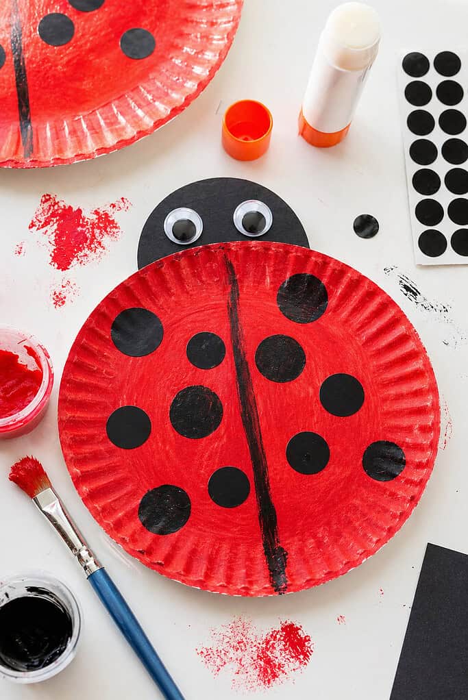 A paper plate painted a rich, vibrant red with a smooth but slightly imperfect, hand-painted texture