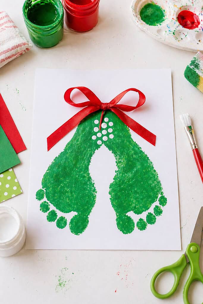two green-painted children’s footprints pressed sole-to-sole, forming a symmetrical mistletoe shape