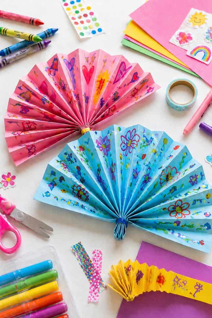 two finished paper fans made from accordion-folded colorful paper or cardstock