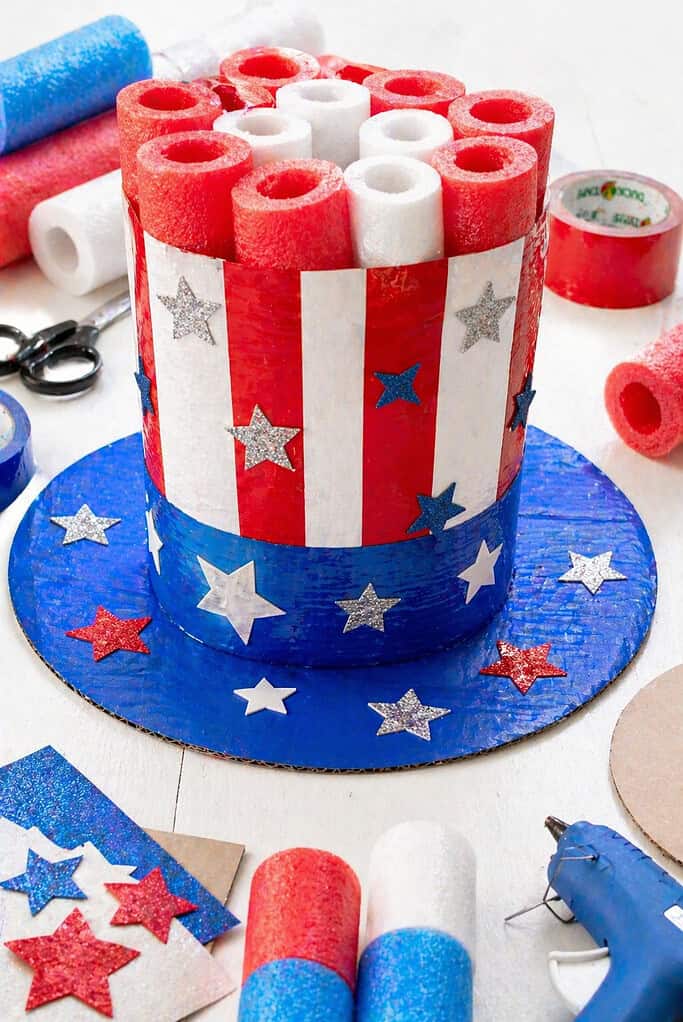 A large, whimsical Uncle Sam–inspired top hat constructed from stacked and shaped pool noodle sections, forming a tall cylindrical crown