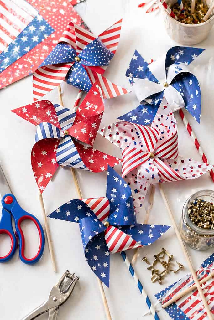 A cluster of handmade pinwheels crafted from patriotic scrapbook paper in red, white, and blue patterns (stripes, stars, polka dots).