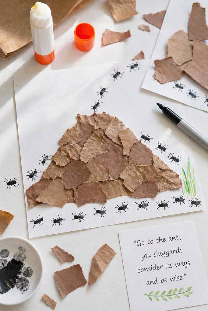 A sheet of paper with a textured mound made from torn pieces of brown construction paper and recycled grocery bag paper, layered to form a natural, uneven ant hill shape.