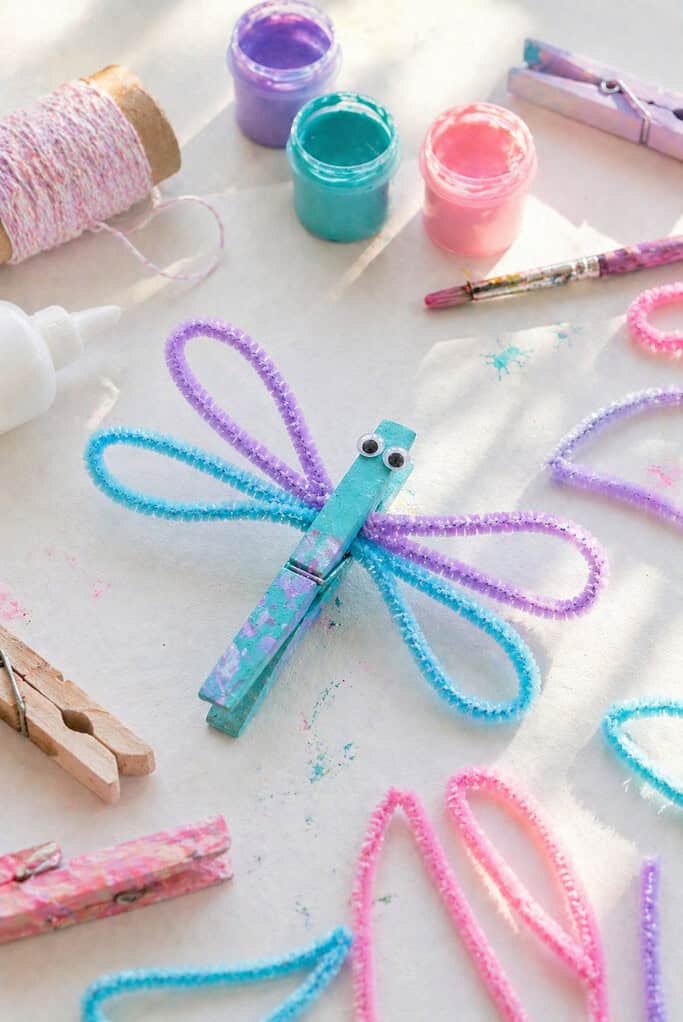 A wooden clothespin painted in soft, pretty colors—pastels or vibrant blends like teal, lavender, pink, or sky blue—with visible brushstroke texture