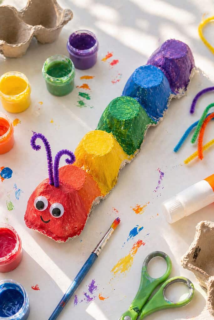 A recycled cardboard egg carton cut into a row of connected cups, forming a caterpillar body