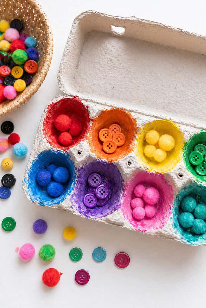 an open egg carton with each cup painted in a different bright, cheerful color (or pairs of matching colors).