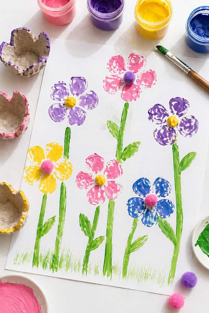 a sheet of white paper featuring several stamped flowers made using egg carton cups.
