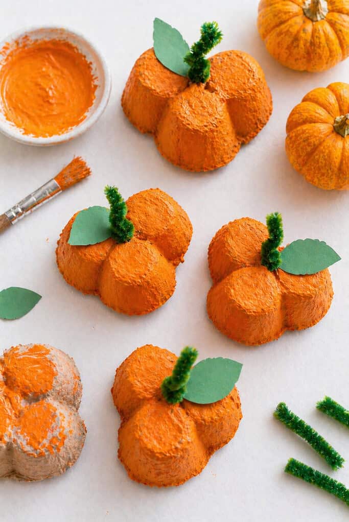 several small pumpkins made from three connected egg carton cups glued together to form a clustered, rounded shape.