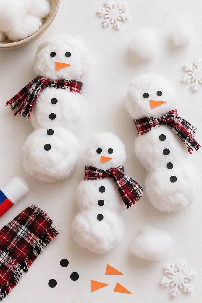 several small snowmen made from three egg carton cups glued together in a vertical row to form the body