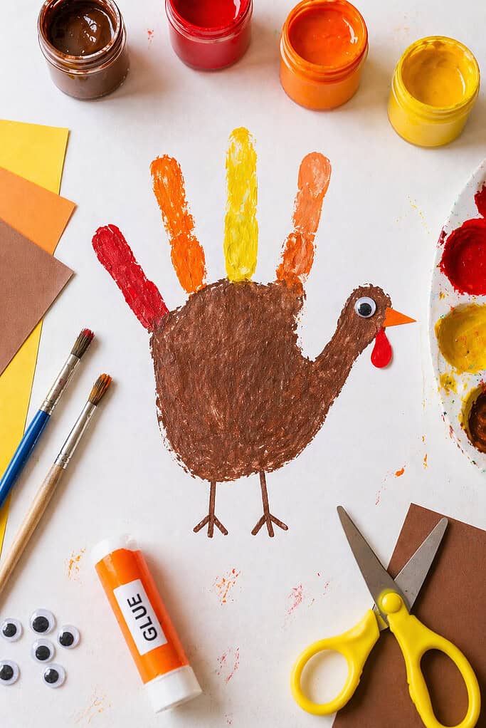 a finished handprint turkey craft made from a child’s handprint stamped in rich brown paint to form the turkey’s body