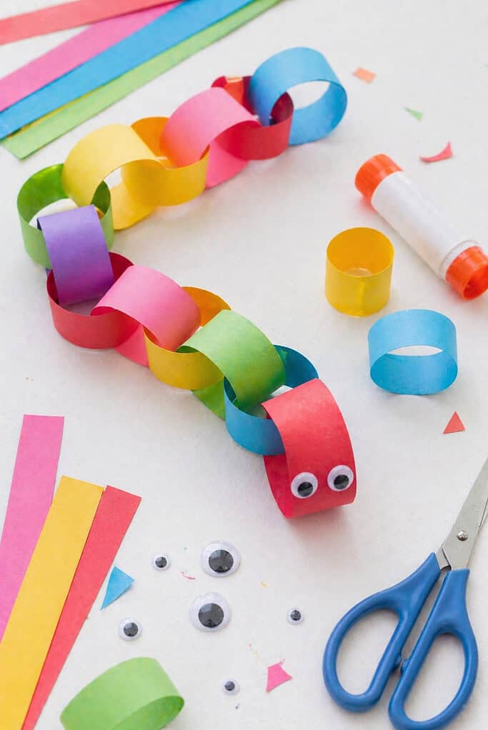 A long paper chain made from interlinked loops of brightly colored paper strips—reds, yellows, greens, blues, and pinks