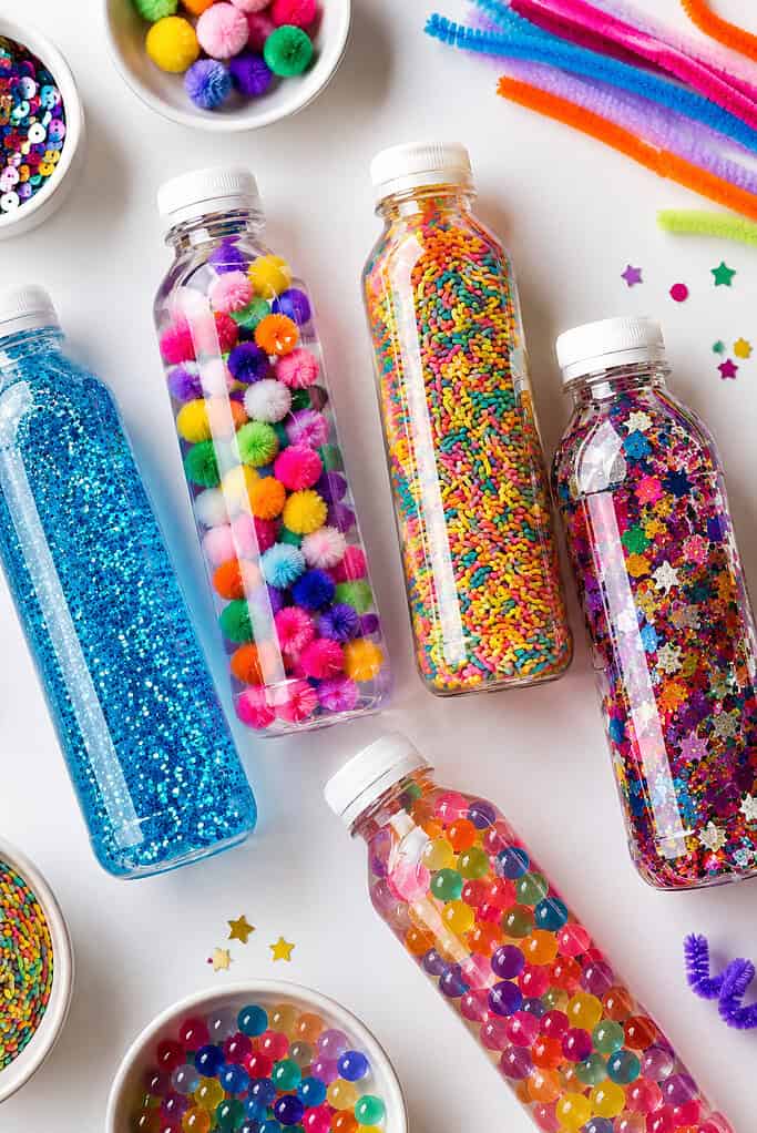 Multiple clear sensory bottles arranged organically across the frame, partially overlapping for depth and visual interest