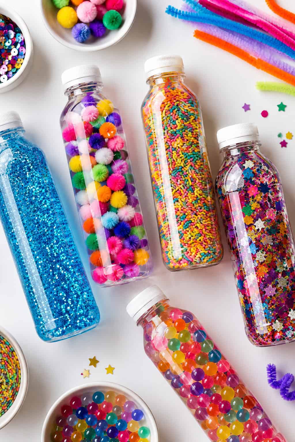 Multiple clear sensory bottles arranged organically across the frame, partially overlapping for depth and visual interest