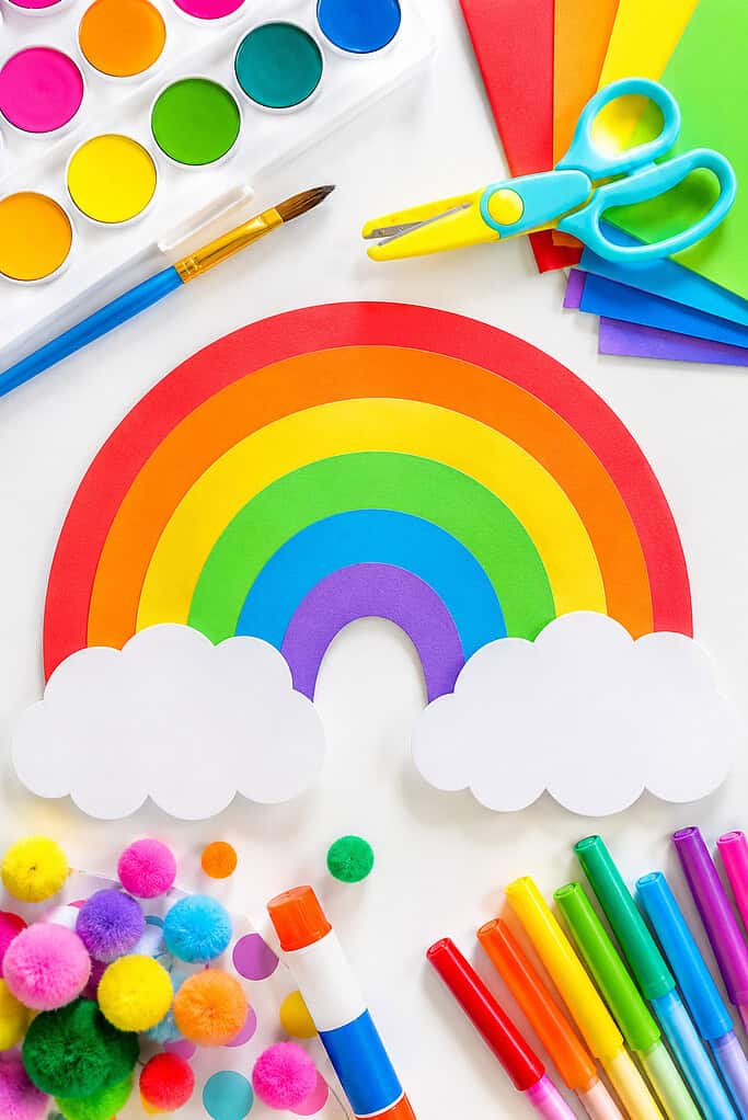 rainbow-themed kids craft supplies and handmade craft elements spread organically across the table