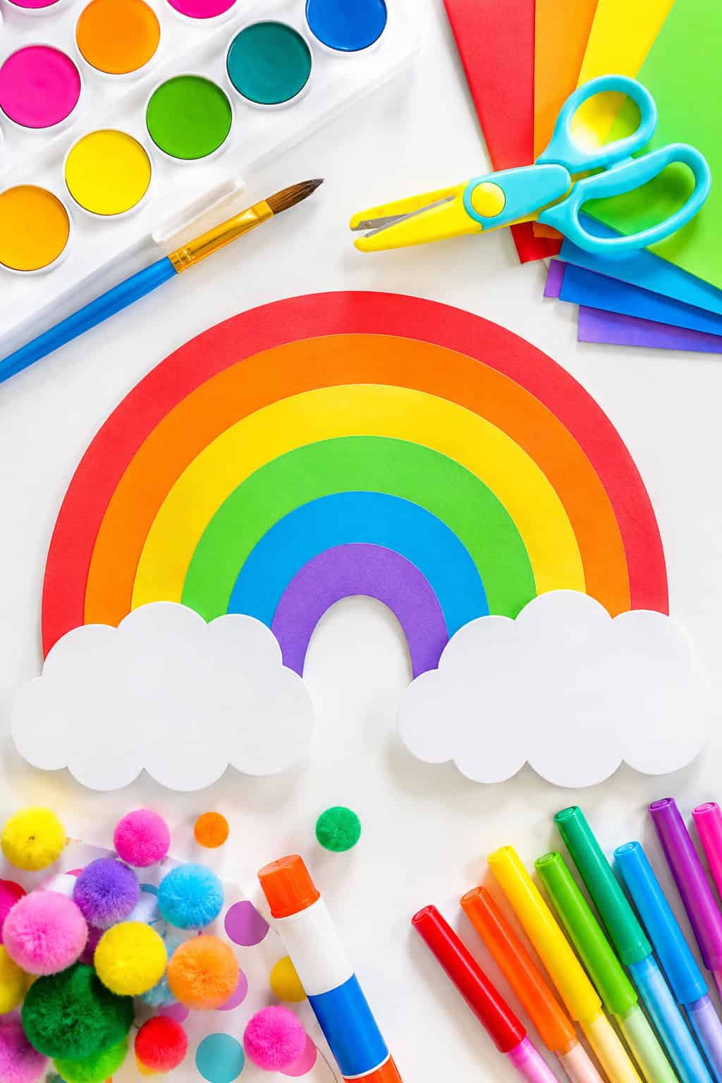 rainbow-themed kids craft supplies and handmade craft elements spread organically across the table
