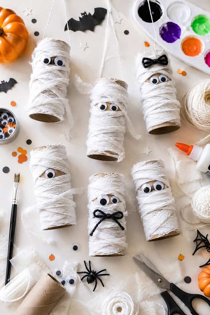 several handmade mummy characters created from recycled toilet paper rolls wrapped in soft white yarn and gauze strips