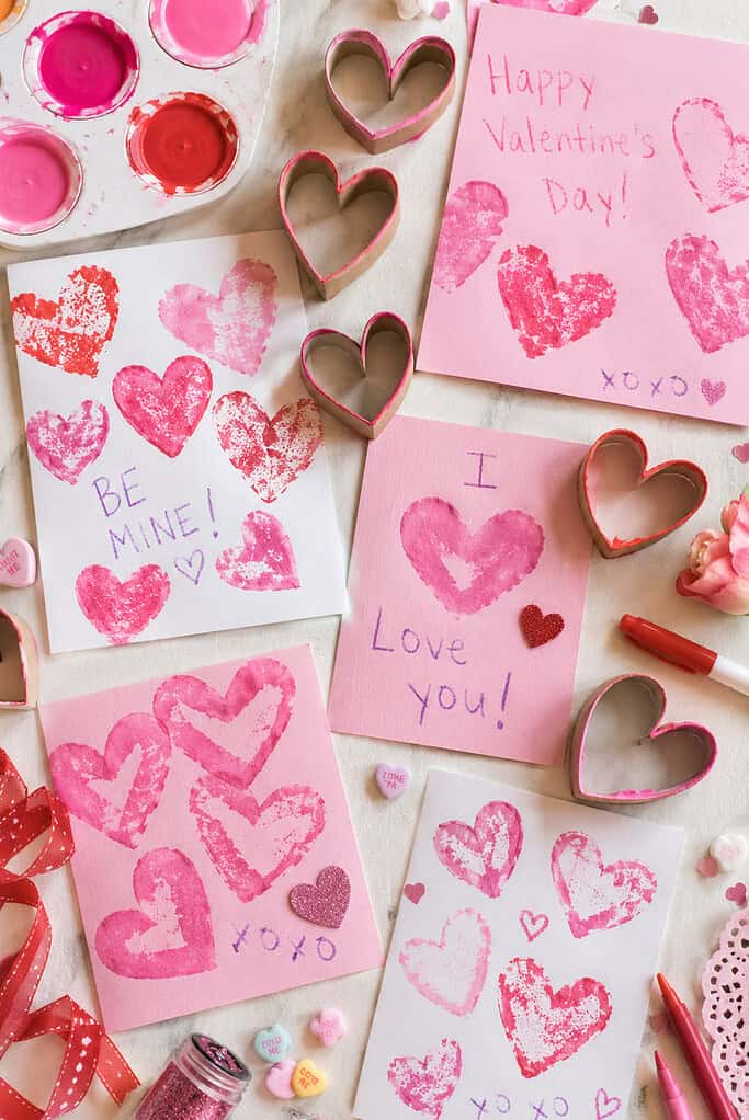 handmade heart prints created using recycled toilet paper rolls pinched into heart shapes and dipped into vibrant red and pink paint