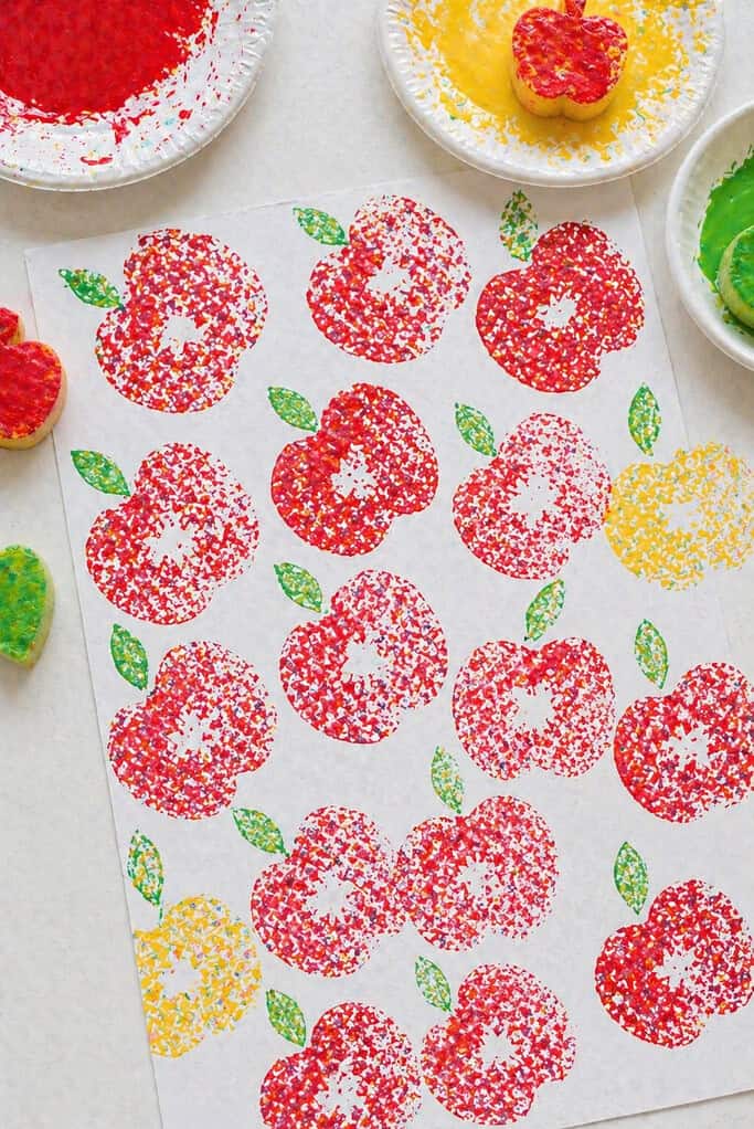 a sheet of cardstock filled with repeated apple stamp prints, arranged like a loose orchard pattern.
