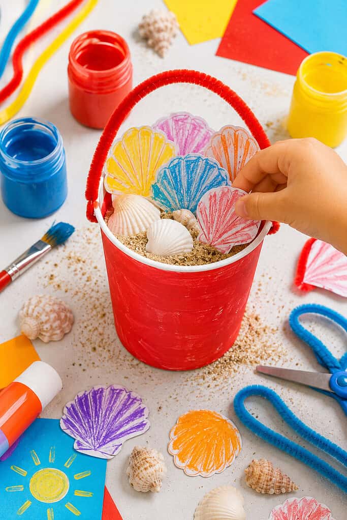 a small handmade beach bucket craft created from a painted paper cup or clean yogurt container