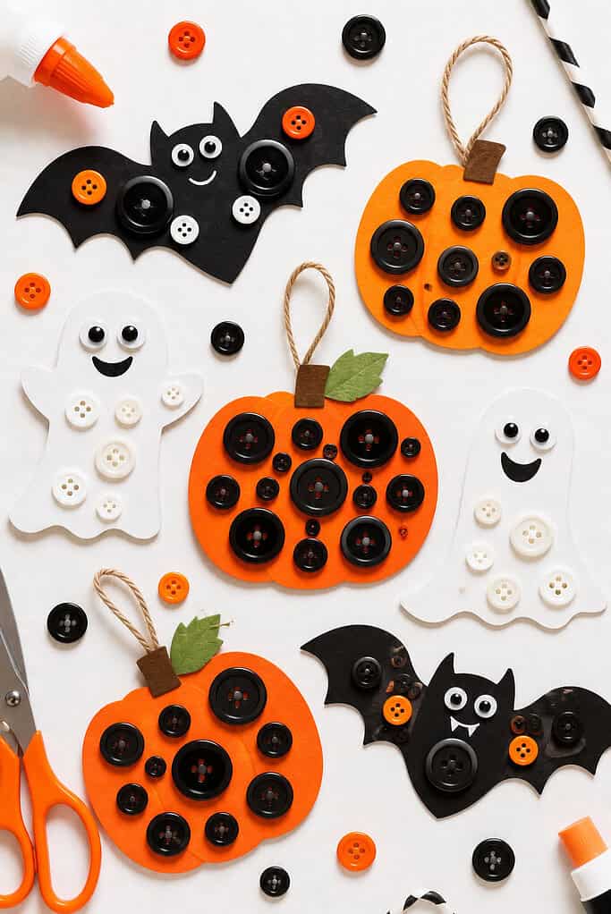 cheerful Halloween-themed crafts made from orange, black, and white cardstock, including pumpkins, bats, and friendly ghost shapes decorated with colorful buttons.