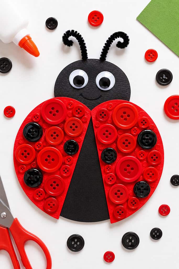 a handmade ladybug craft created from cardstock or painted paper, featuring bright red buttons glued onto the wings