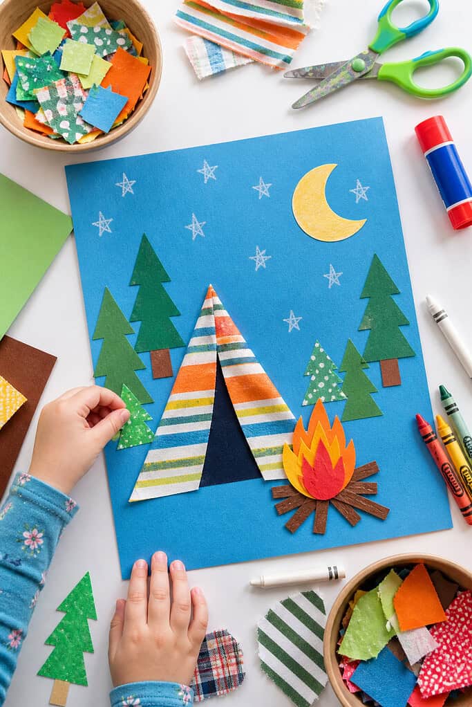 a completed camping-themed preschool collage on a sky-blue sheet of cardstock