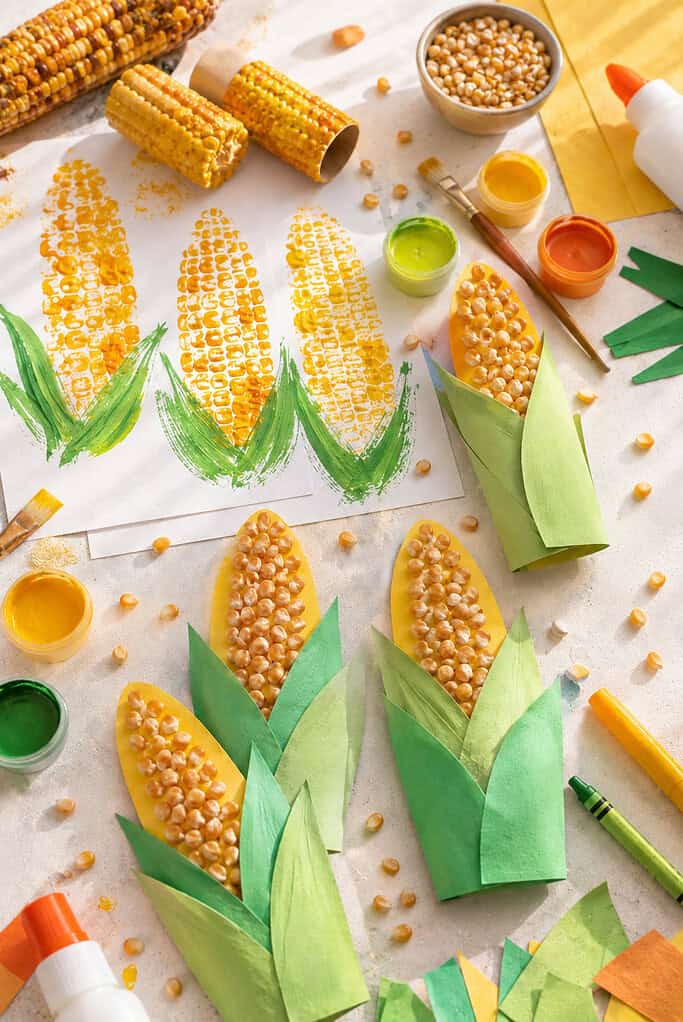 multiple corn-themed crafts arranged across the table in a warm autumn-inspired layout