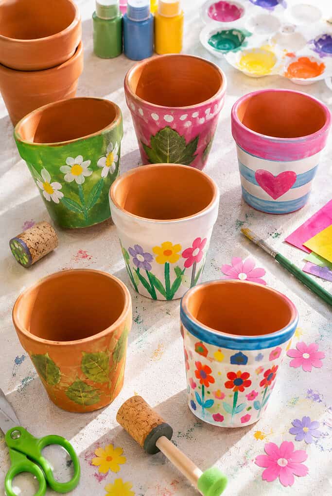 small terracotta flower pots and decorated paper cups transformed into cheerful handmade garden crafts.