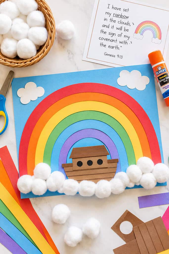 A small brown paper ark cutout positioned near the bottom center of the rainbow
