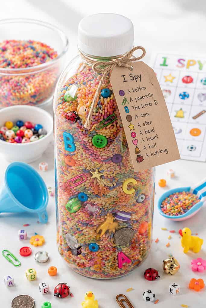 one clear plastic sensory bottle filled about three-quarters full with fine rainbow-colored rice 