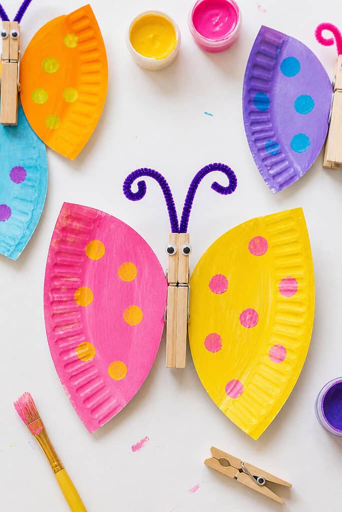 A paper plate cut cleanly in half to form two wings, each painted in a different vibrant color