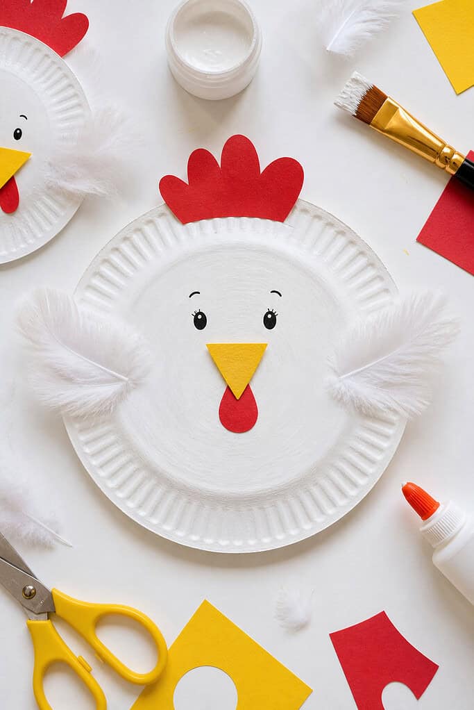 A chicken made of paper plate painted white with visible, slightly uneven brush strokes for a natural, childlike finish.