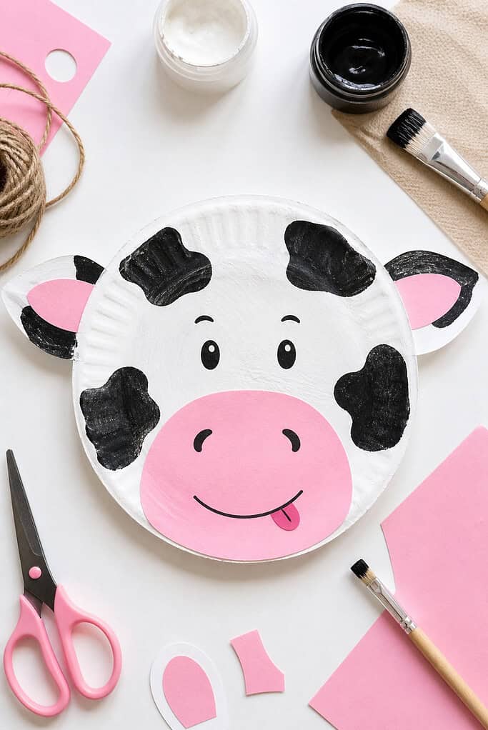 A cow made of paper plate painted white with visible brush strokes for a natural, childlike texture.