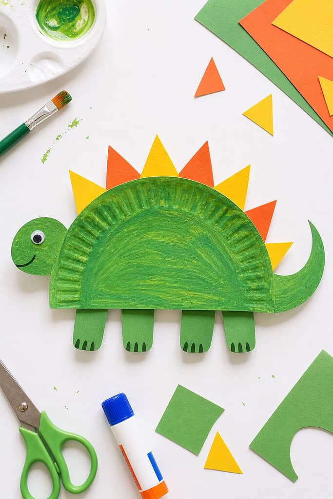 A paper plate cut cleanly in half, with one half used as the rounded body of a stegosaurus