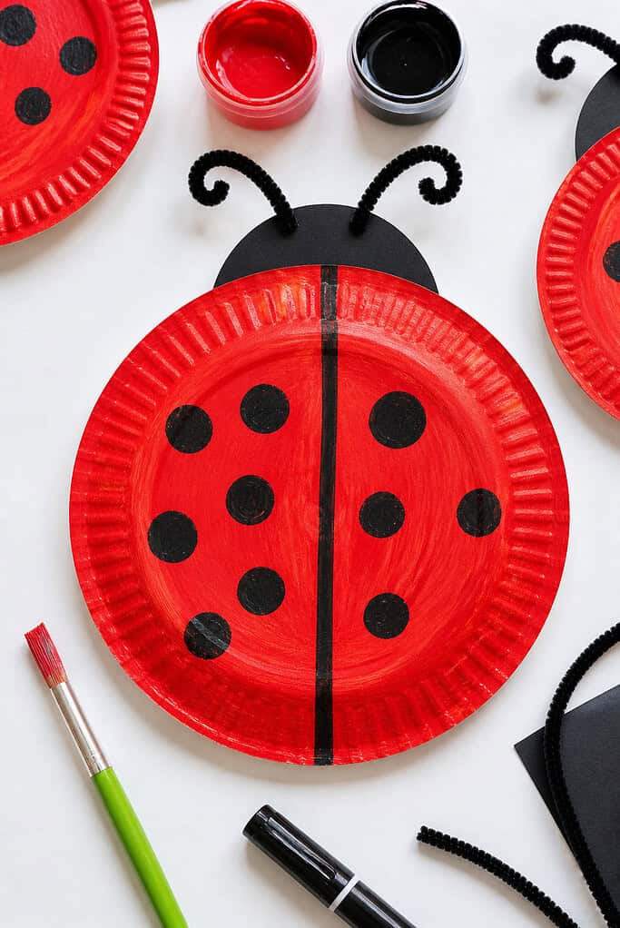 A paper plate painted a vibrant, slightly textured red, with visible brush strokes for a natural, childlike finish