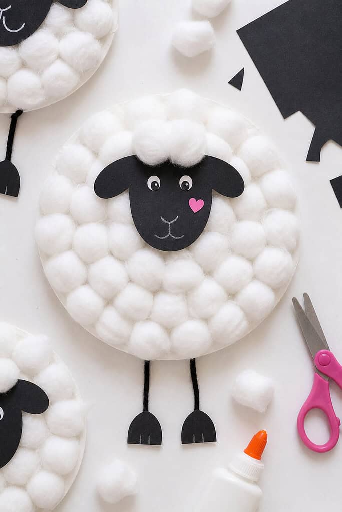 A paper plate covered generously with fluffy cotton balls, creating a full, textured wool effect.