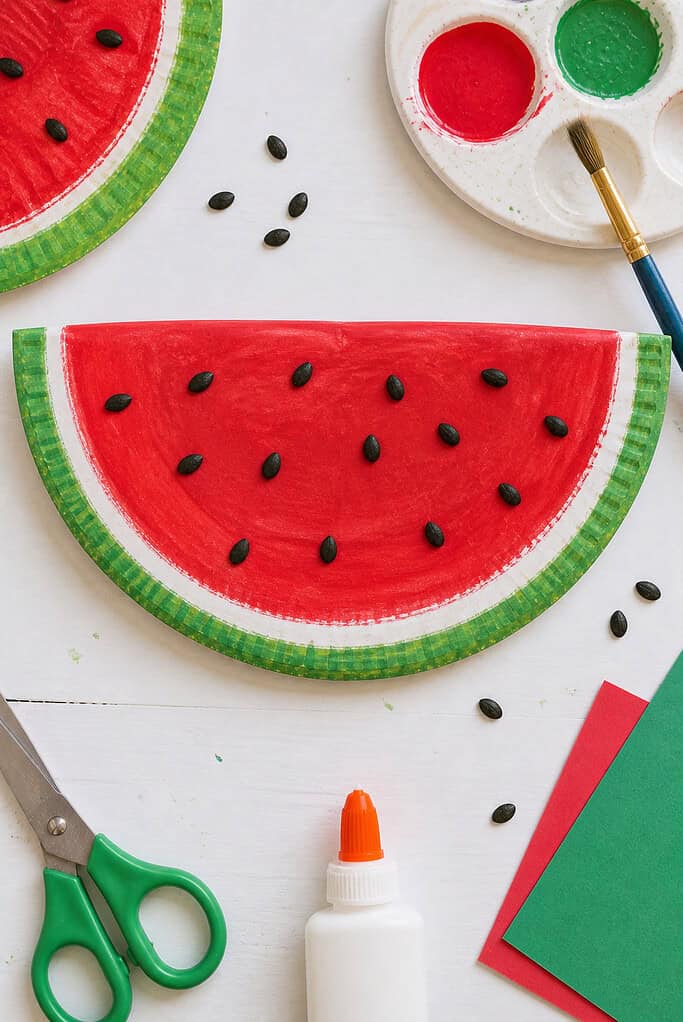 A paper plate cut cleanly in half to resemble a watermelon slice.