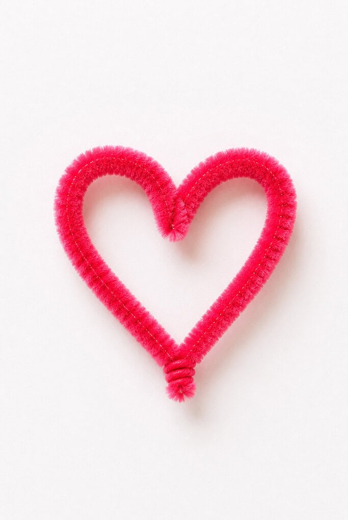 a handmade heart crafted from a fuzzy pink or red pipe cleaner bent into a soft symmetrical heart shape
