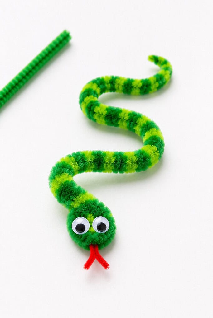 a handmade snake crafted from a single fuzzy pipe cleaner curled into a soft S-shape.