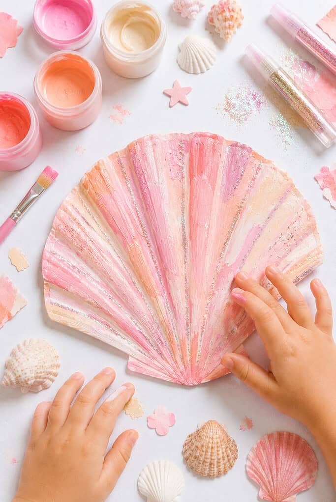 a paper plate cut in half and transformed into a large seashell craft.